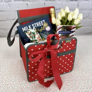 Red Fabric Storage Bin with White Dots filled with various gifts and decorated with bow