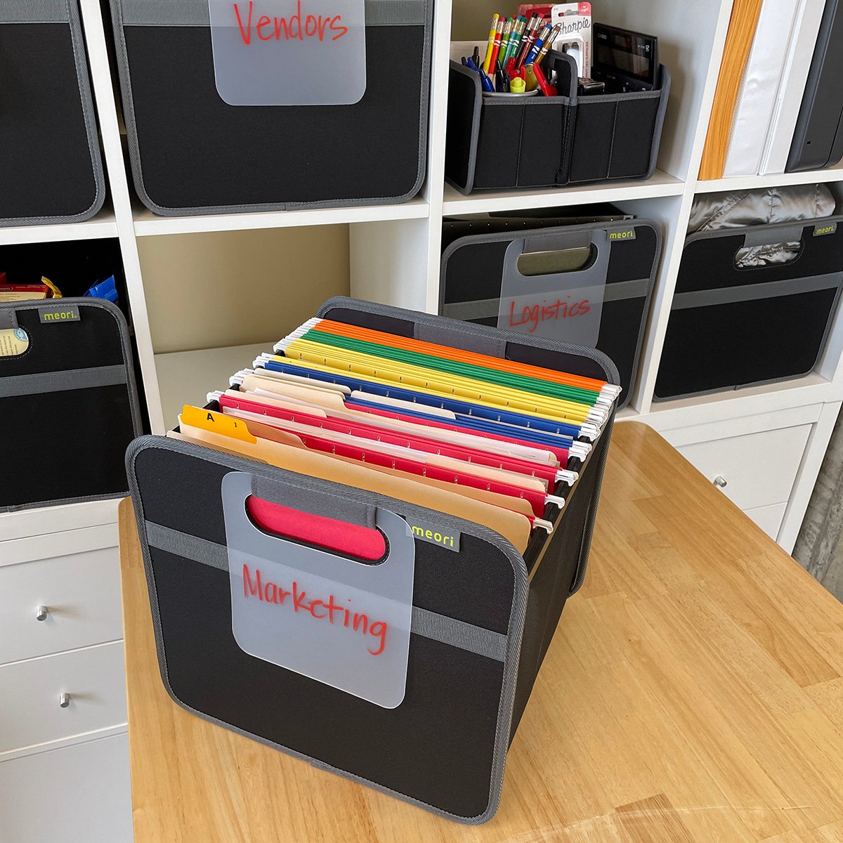 A100094-16-meori-Hanging-File-Box-Lava-Black-LST Black Hanging File Box with file folders on a desk in front of a shelf filled with meori boxes