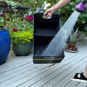 Black Collapsible Trunk Organizer shown being hosed off in front of flower pots on patio