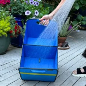 Blue Collapsible Trunk Organizer shown being hosed off in front of flower pots on patio