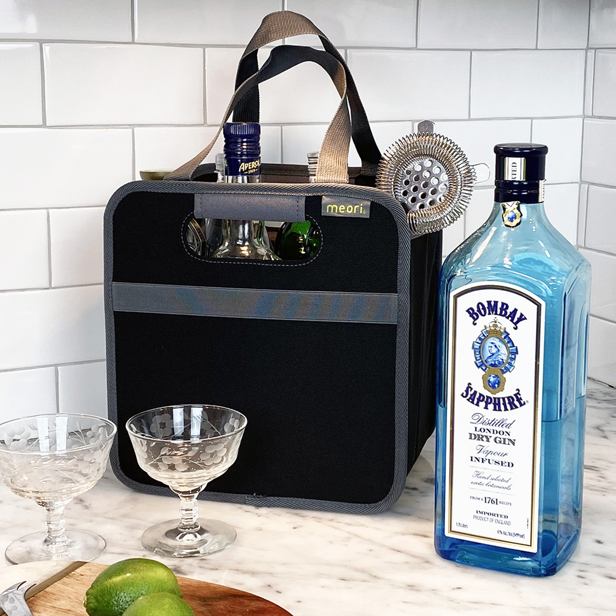 Black 6 Bottle Wine Tote sitting on kitchen counter with 2 cocktail glasses and bottle in front of it