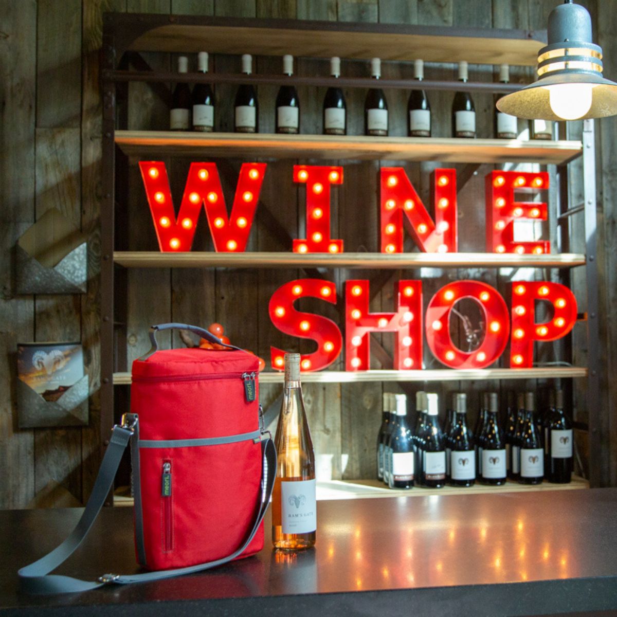 A100861-06-meori-Insulated-Wine-Tote-2-Bottles-Hibiscus-Red-LST Red 2 Bottle Insulated Wine Bag next to bottle of rose in wine shop