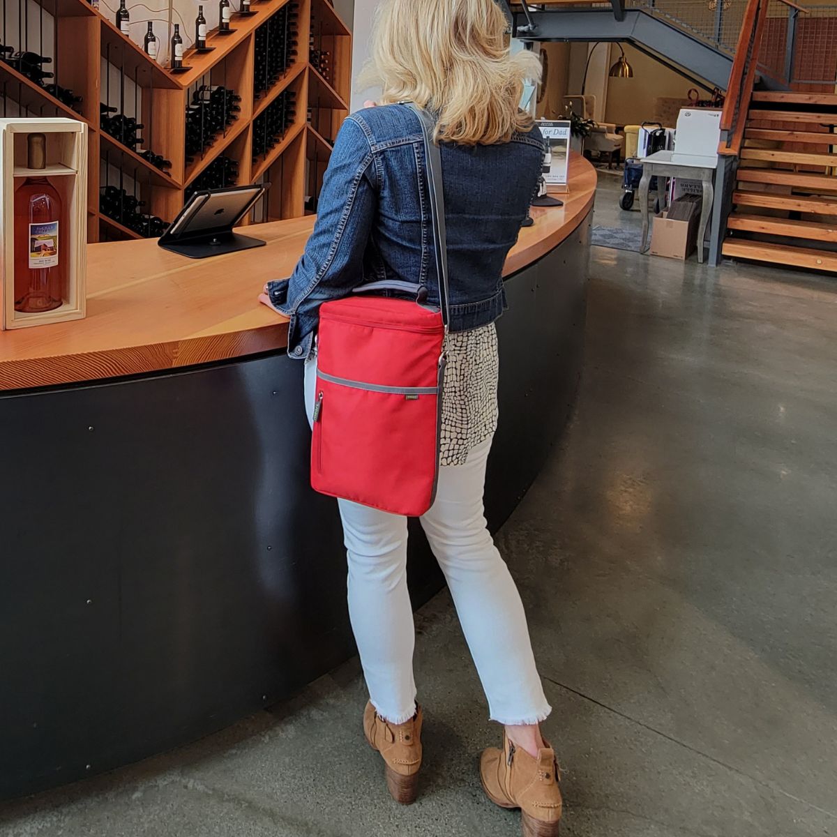 A100861-10-meori-Insulated-Wine-Tote-2-Bottles-Hibiscus-Red-LST Woman with Red 2 Bottle Insulated Wine Bag hanging over her shoulder waiting at counter