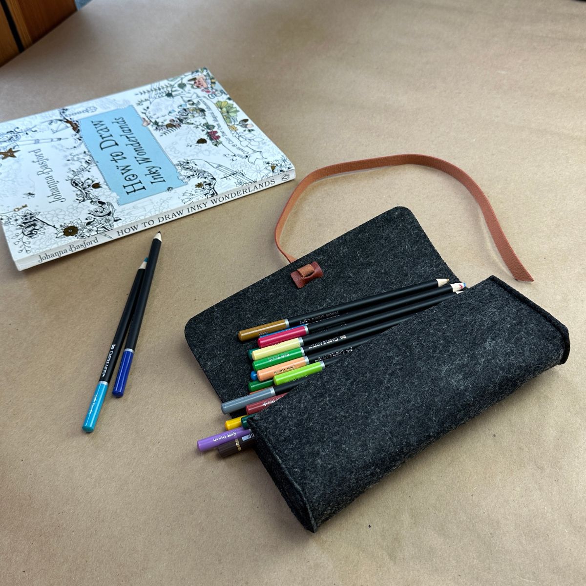 A100876-8-meori-Felt-Pouch-Anthrazite-Grey Open grey felt pouch with colorful pencil showing next to coloring book on craft table