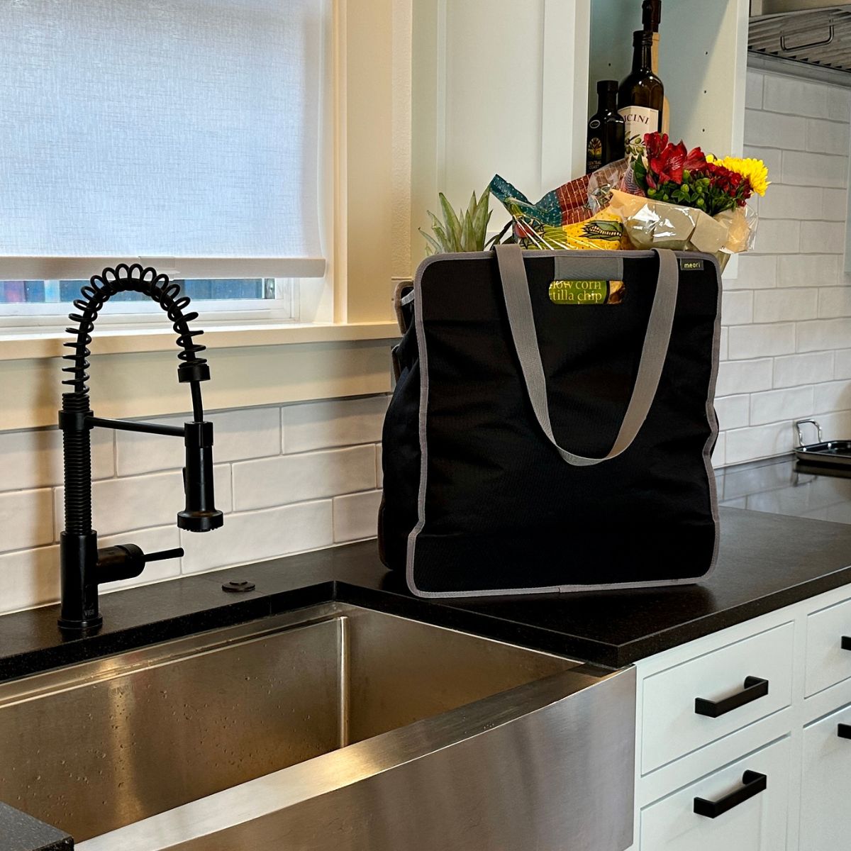 A100882-11-meori-Large-Utility-Tote-Lava-Black Large Black Utility tote filledwith groceries and flowers sitting on kitchen counter top