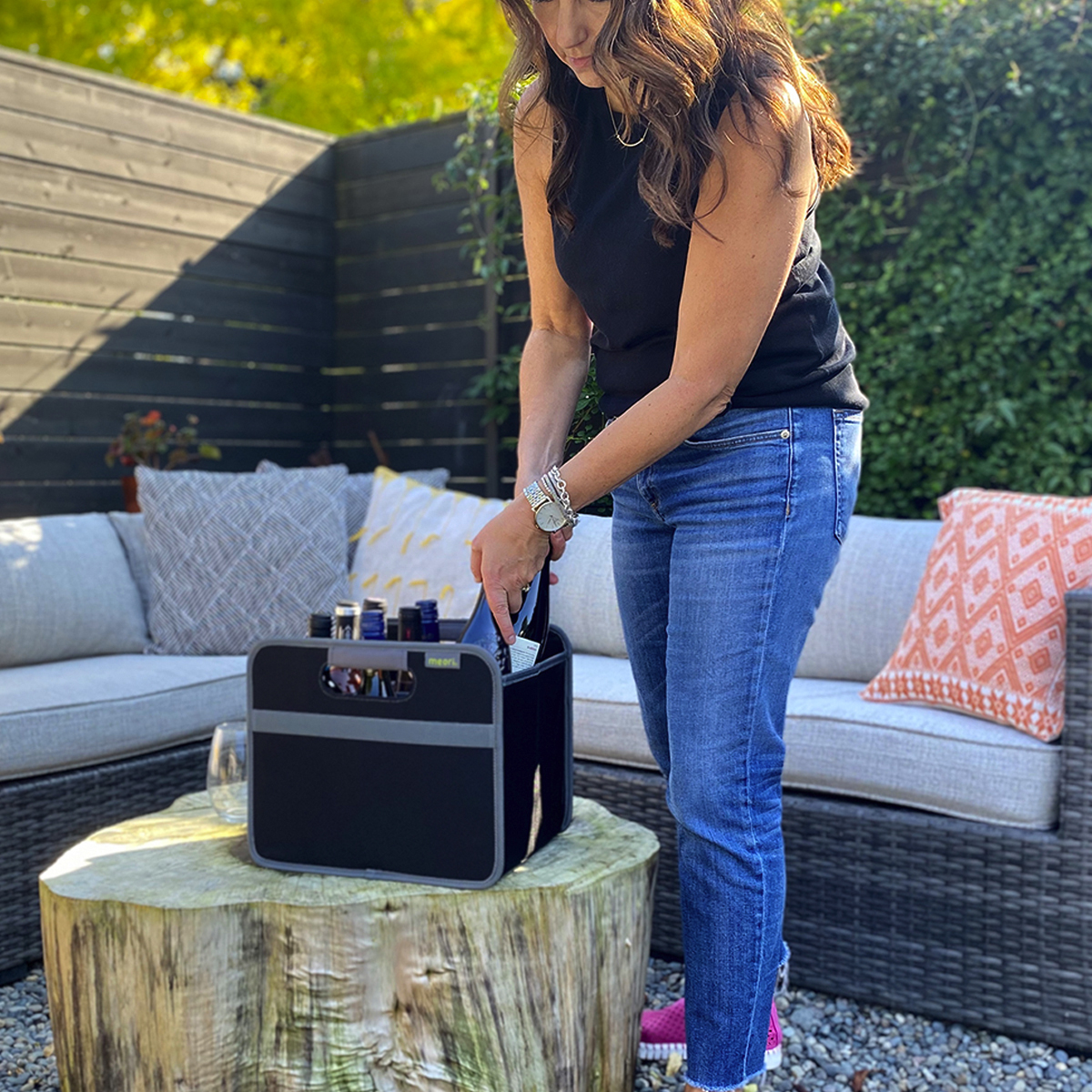 Woman taking out wine bottle out of a Black 12 Bottle Wine Carry Bag sitting on a rustic table