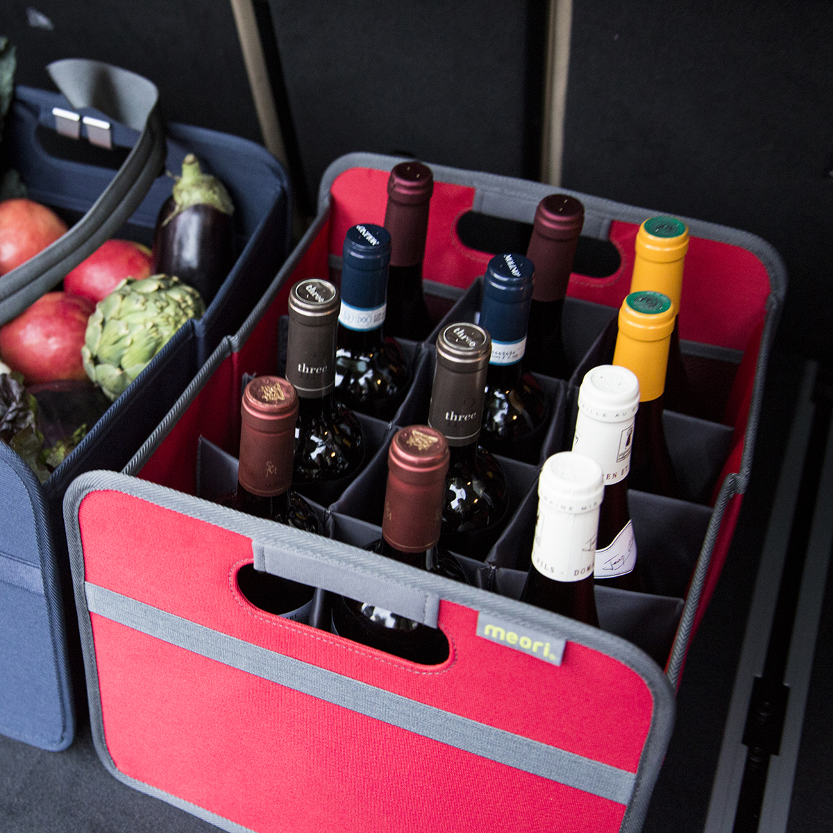 B100296-11-meori-12-Bottle-Wine-Carrier-Hibiscus-Red-LST Red 12 Bottle Wine Carry Bag filled with bottles in the back of a trunk next to grocery basket