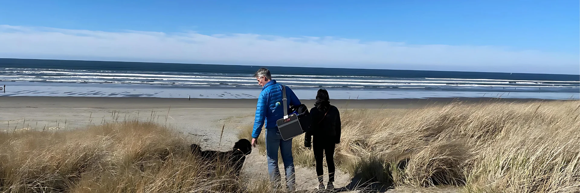 man and woman and dog on the beach carrying meori trunk organizer